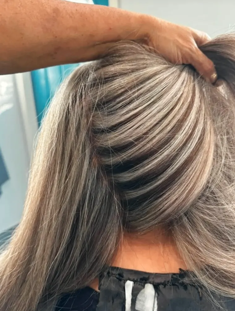 Diana lifting a section of hair to show fine, dimensional highlights.