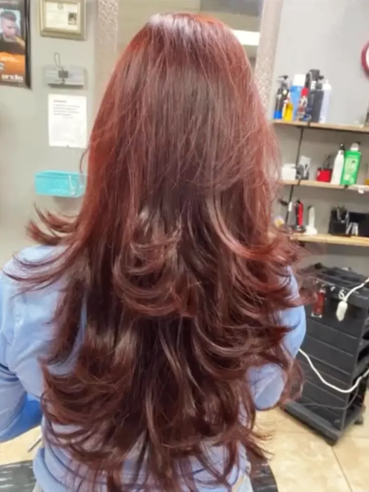 Long, glossy red hair with soft layers, styled at Maribella's.
